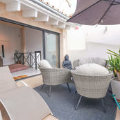Sunbeds and armchairs on a sunny balcony.
