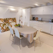 Light and beautiful dining room and kitchen. Round dining room table with six white chairs. White kitchen interior design. 