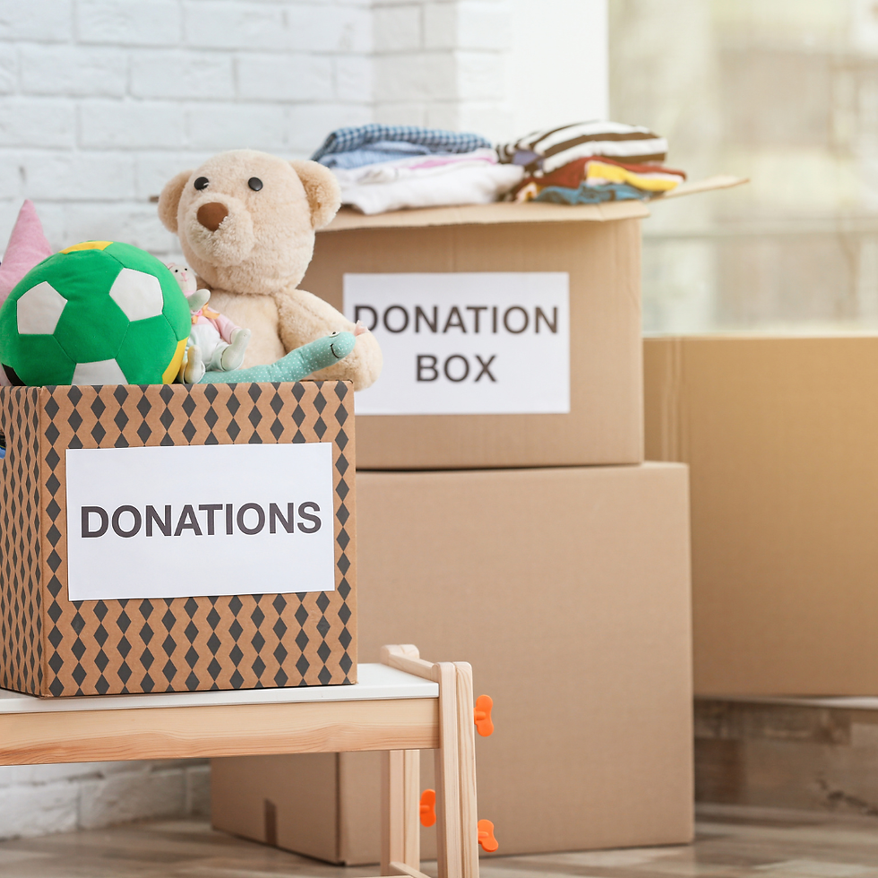 Cardboard boxes labeled "Donations" filled with toys and clothes in a bright room. Cozy atmosphere, brick wall in the background.