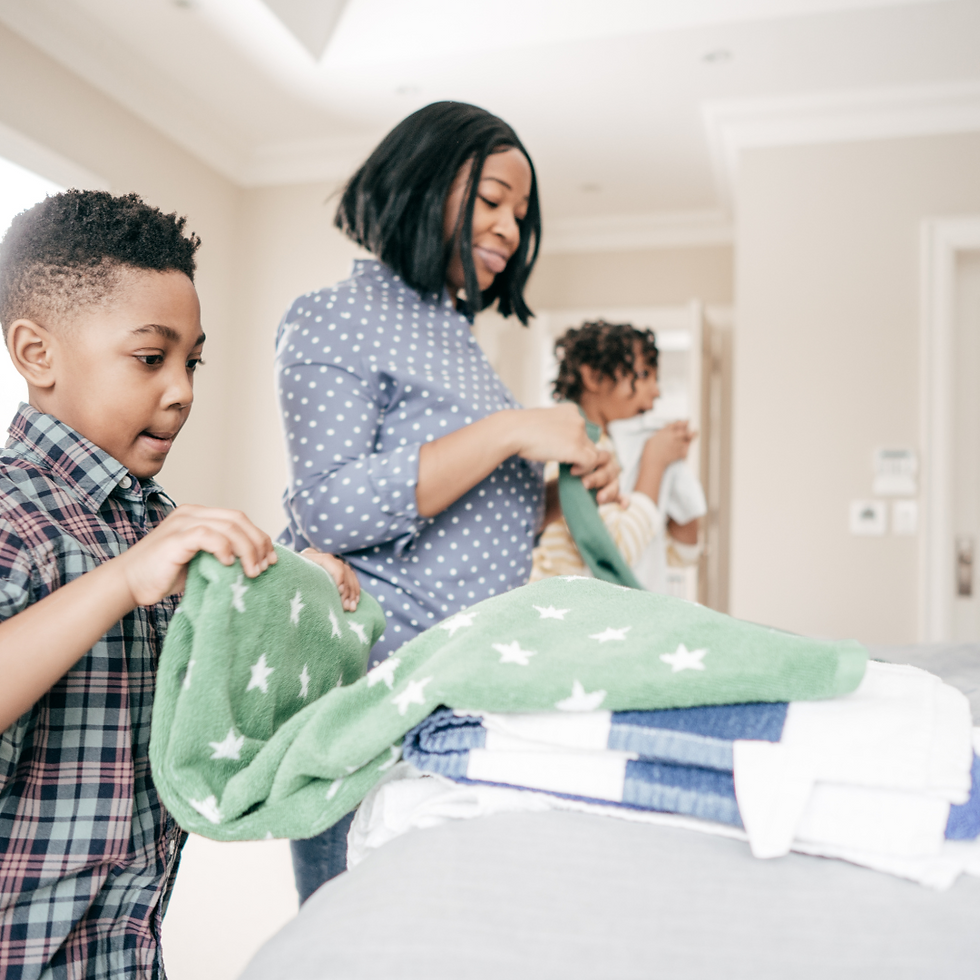 Mother and children folding laundry together at home, illustrating the importance of raising organized kids with habits and systems through shared household routines.