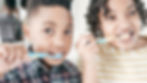Two kids brushing teeth as part of daily routine — raising organized kids with healthy habits.