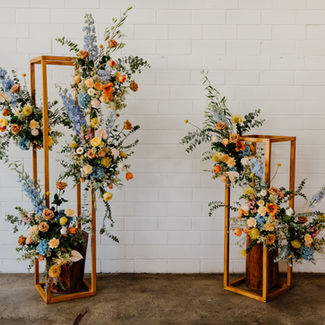 Orange and blue floral arrangement on wood stands, wedding reception styling