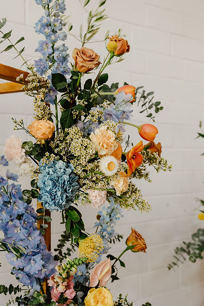 Colourful wedding floral arrangement with blue, peach, orange and yellow seasonal flowers