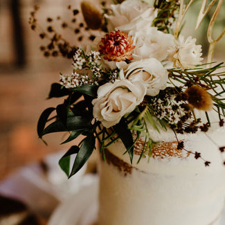 White wedding cake tier with cream roses and dried flowers