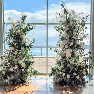 White and cream floral columns at a waterside wedding ceremony