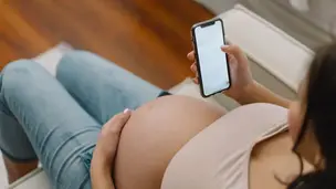 pregnant woman sitting down looking at her phone
