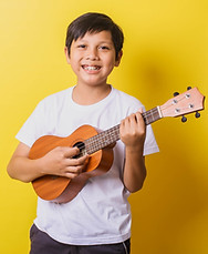 Happy little boy playing ukulele isolated on yellow background.jpg