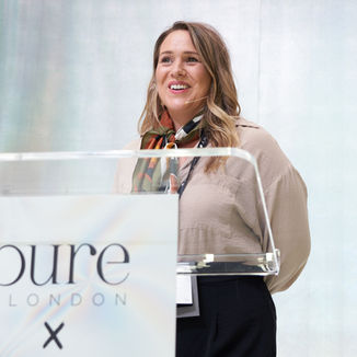 a woman stands behind a podium that says pure london