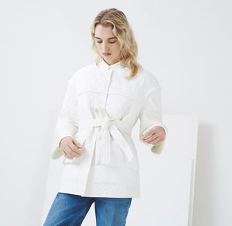 a woman wearing a white jacket and blue jeans