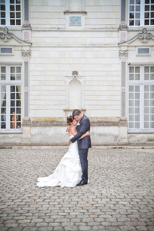 Mariés s'enlaçant dans la cour du chateau
