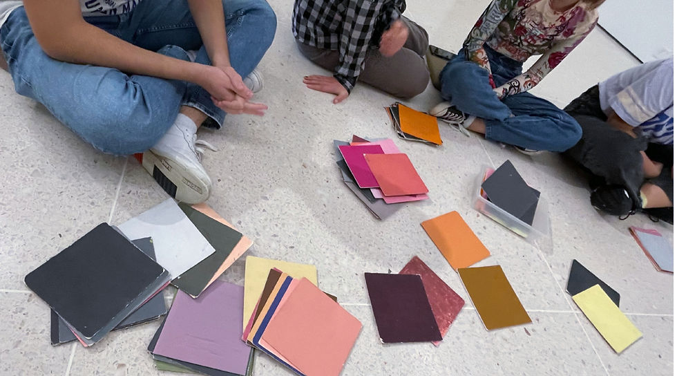 Participants at the museum engage in a lively discussion, using colorful cards to explore and match the artist's palette choices.