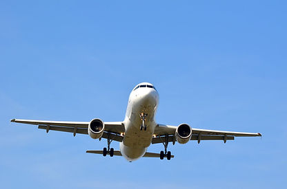 Weißes Passagierflugzeug mit ausgefahrenem Fahrwerk am klaren blauen Himmel.