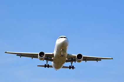 Weißes Passagierflugzeug mit ausgefahrenem Fahrwerk am klaren blauen Himmel.