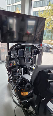 Modernes Flugsimulator-Cockpit mit Armaturenbrett, Joystick und großem Bildschirm.