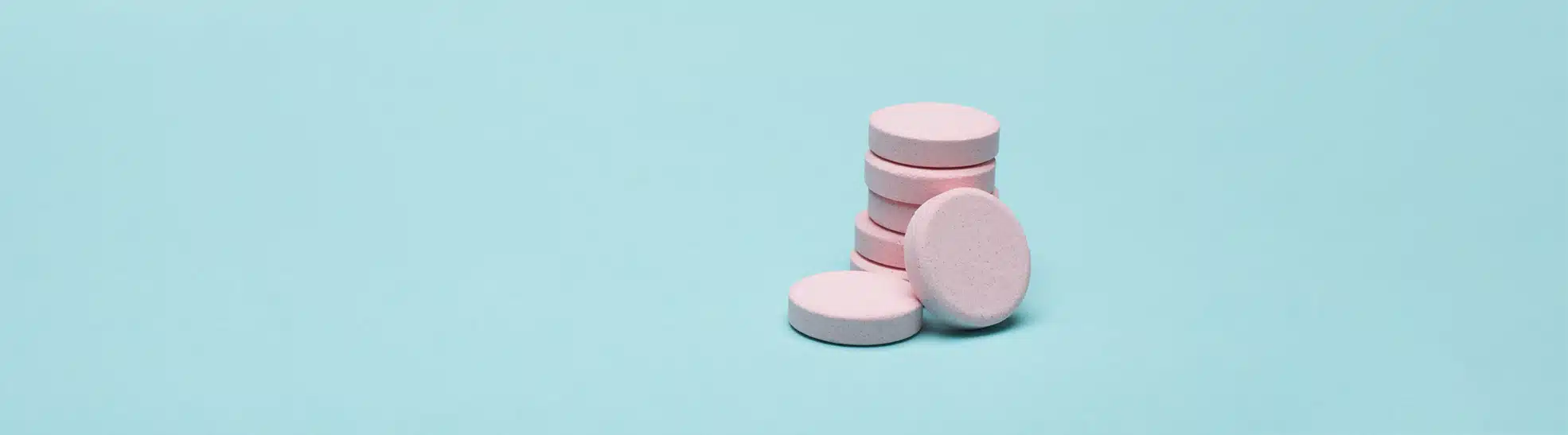 Pink prescription pills on blue pastel coloured background