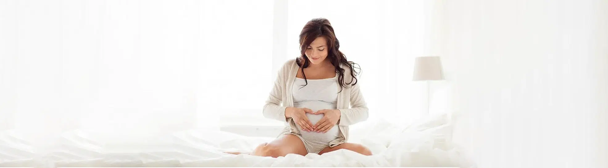 Happy pregnant woman making heart gesture at home copy