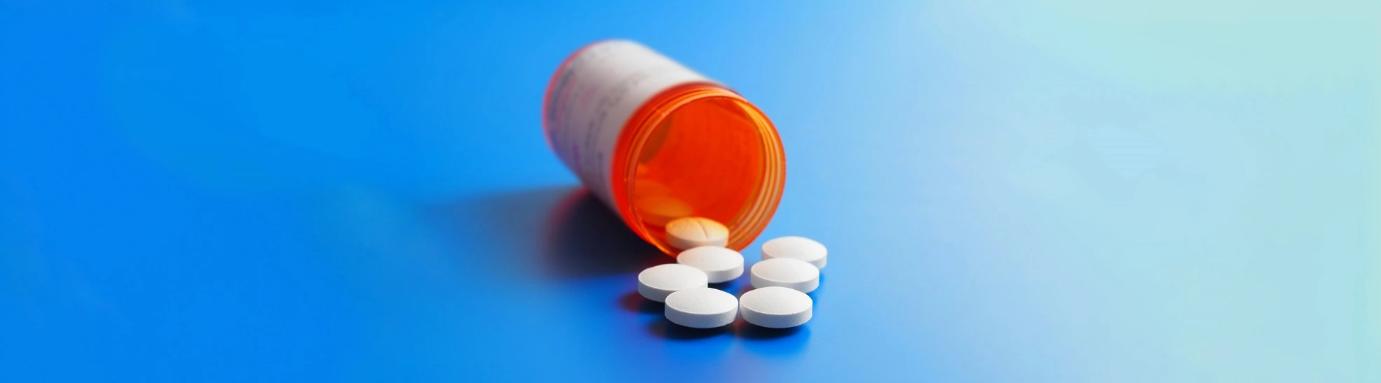 Bottle with pills in gradient blue background. Presentation of synthetic opioid