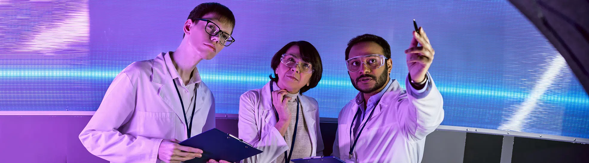 Research team with one person pointing with pen near other scientists in neon lit futuristic science center, banner copy