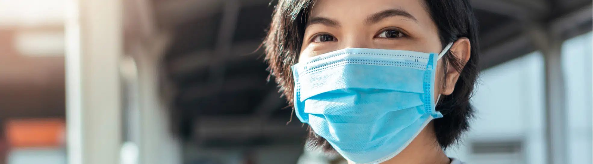 Close up young beautiful asian woman face wearing blue protective face mask looking at camera in new normal life while copy