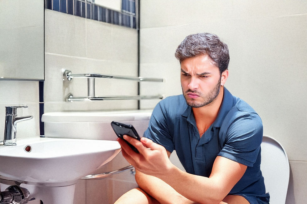 Man in blue shirt sits on toilet, frowning at phone. Mood appears frustrated with what he's reading.