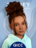 A female sim child with brown curly hair in a bun wears a light blue hoodie.
