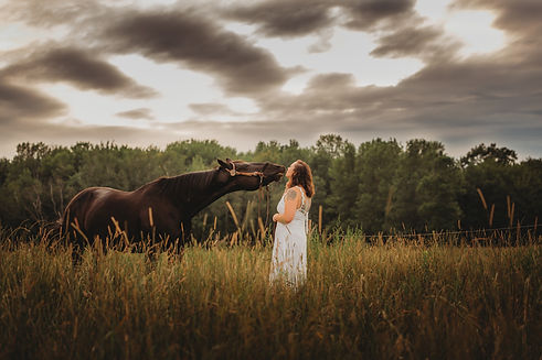 A happy black horse and a compassionate equestrian in a field.