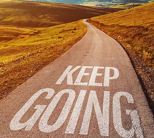Keep going motivational message on asphalt road through countryside landscape, selective f
