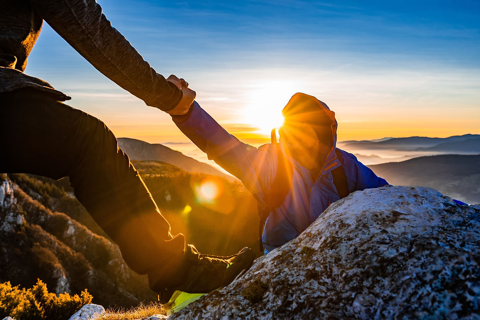 Hiking team people helping each other friend giving a helping hand while climbing up on th