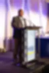 Man standing at a podium addressing an audience.