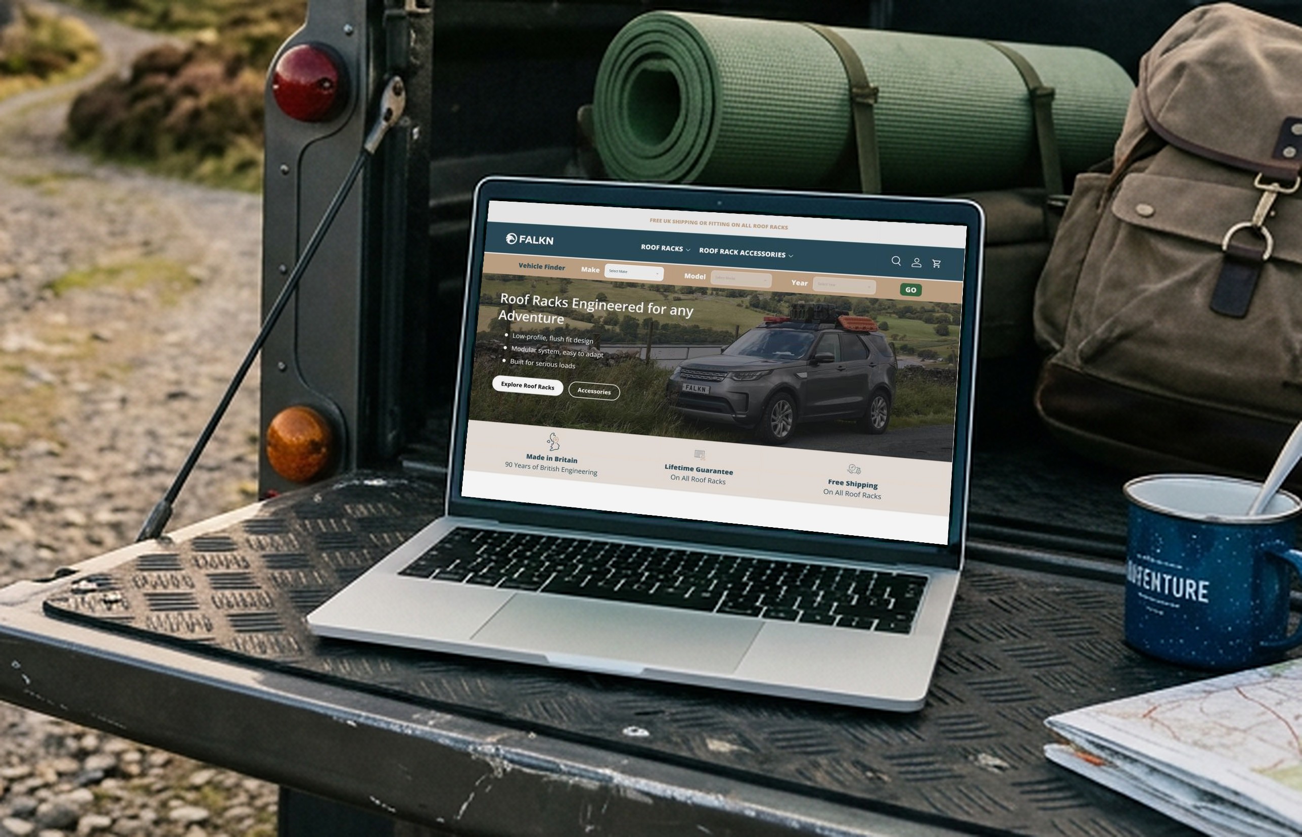 Laptop on the tailgate of a 4x4 in the countryside, showing the FALKN homepage: Roof Racks Engineered for any Adventure