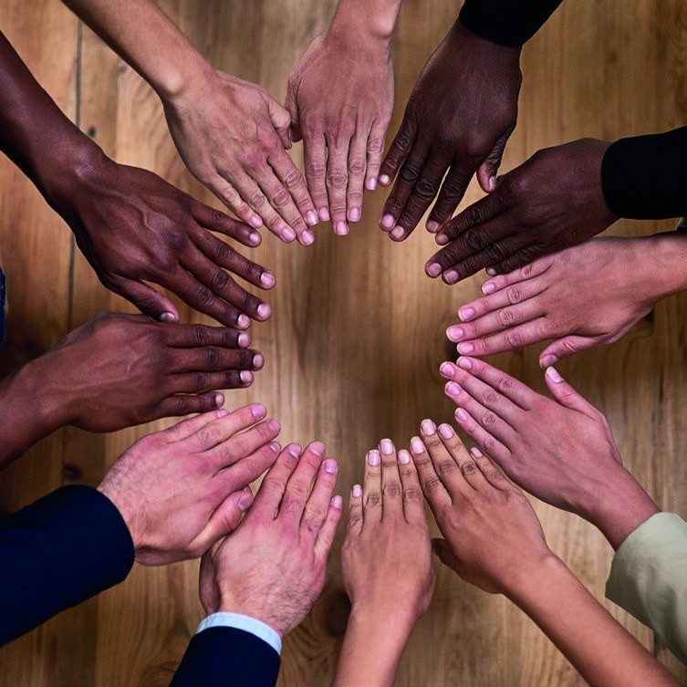 A diverse team joining hands around a table