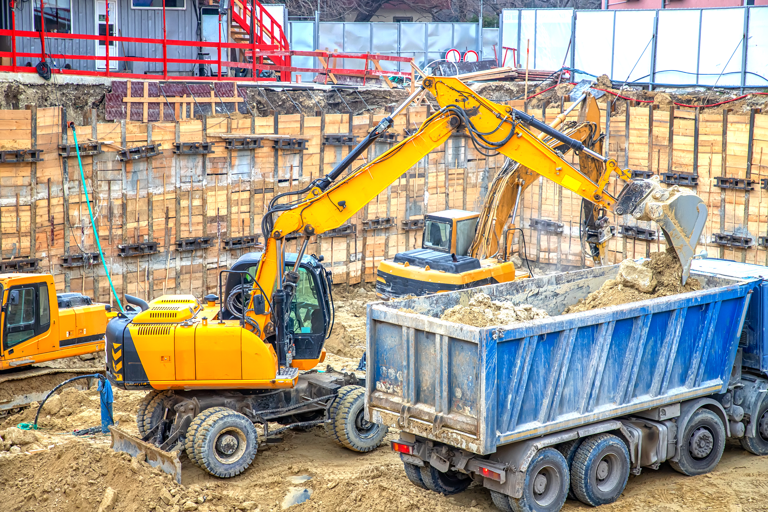An excavator at a construction site, digging up soil with its large arm and bucket.
