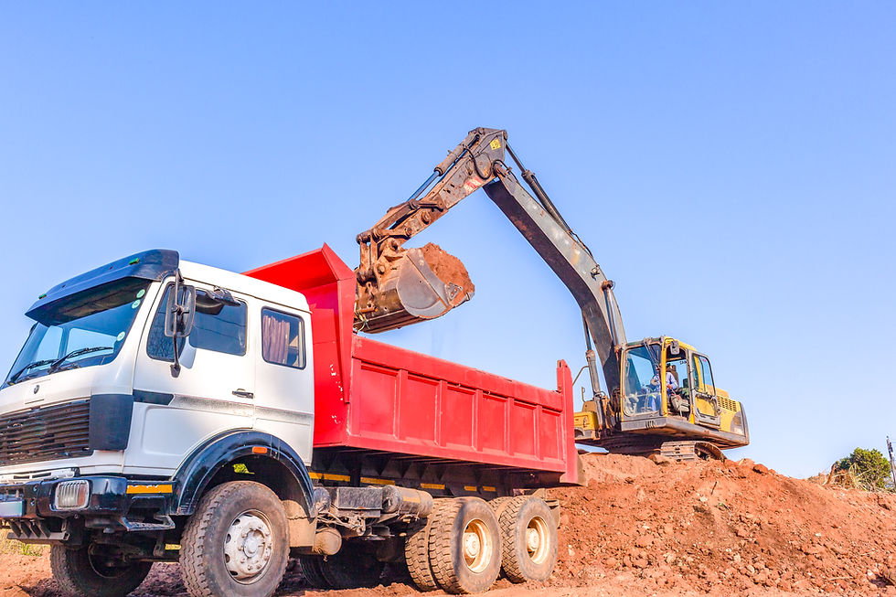 Excavator loading soil into a dump truck at a construction site for compliant Type 2 and Type 3 soil handling and transfer