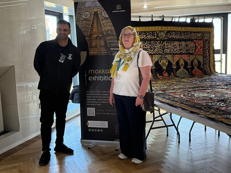 Cllr Imran Safdar and Cllr Alex Vickers stand in front of the majestic Kaaba door cover, captured in