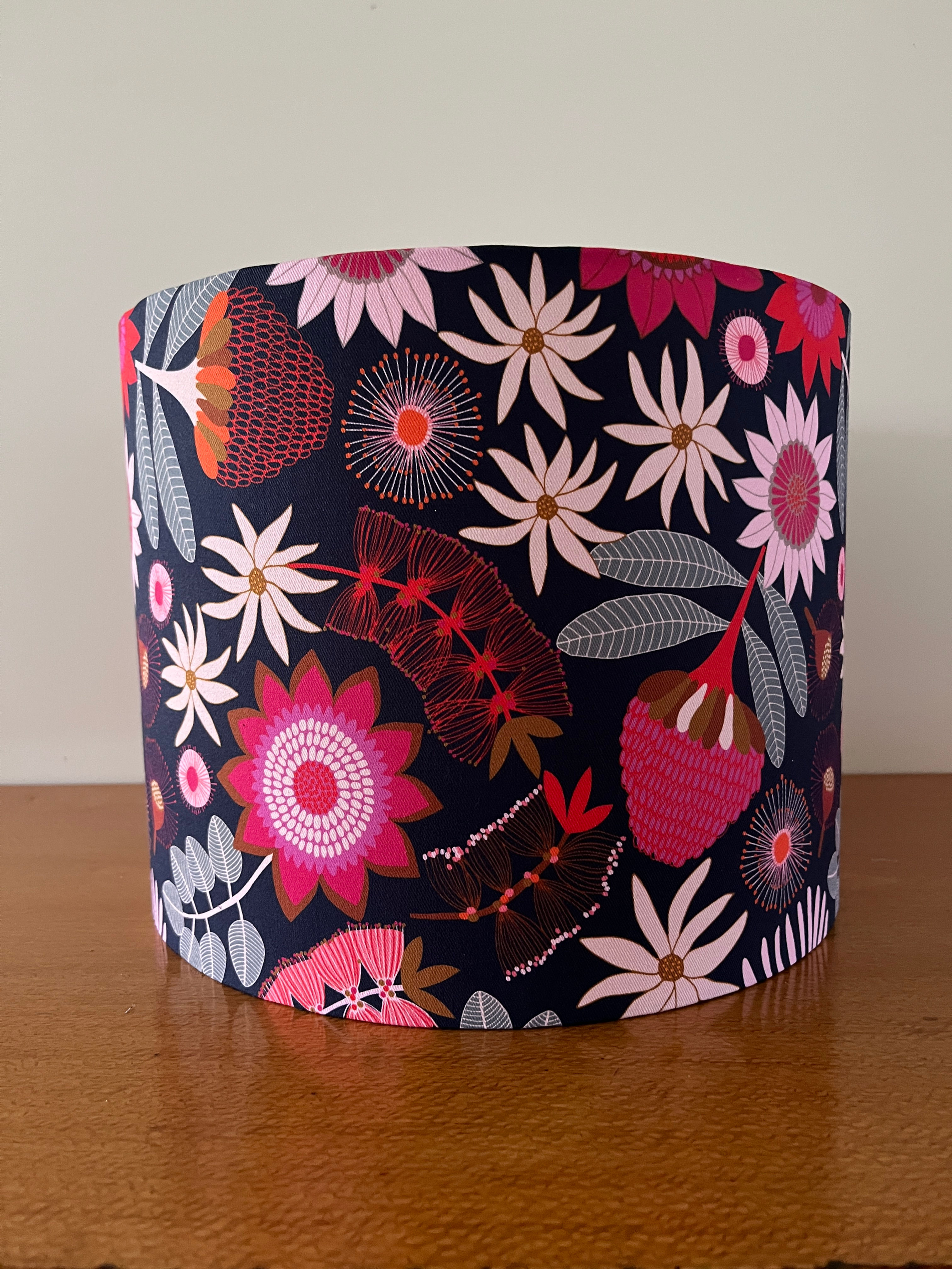 Navy drum lampshade with Australian flowers in shades of pink, red and sage green.