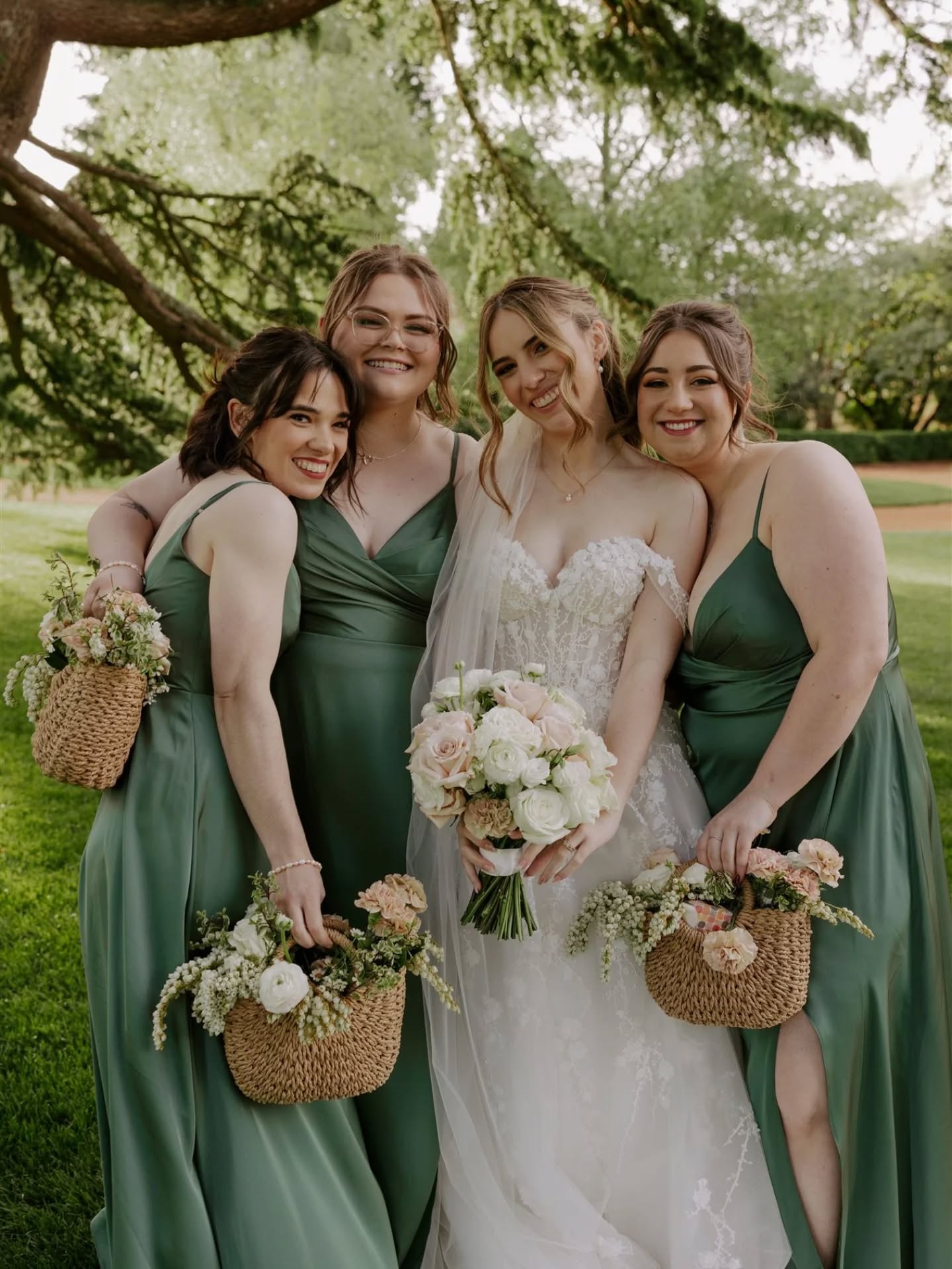 Bride standing with her bridesmaids, bridesmaids holding basket bouquets and wearing green dresses