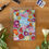 Thumbnail: A6 card with colourful spring tulip design on sky blue background with white Thank You text, with Kraft envelope