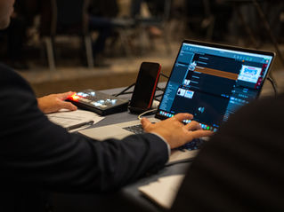 a technical director sitting at a computer working the marketing for an event for a client.