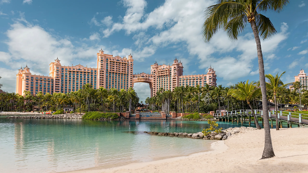 Tropical resort with pink towers and palm trees, set by a calm lagoon and sandy beach under a blue sky. Relaxing, sunny atmosphere.