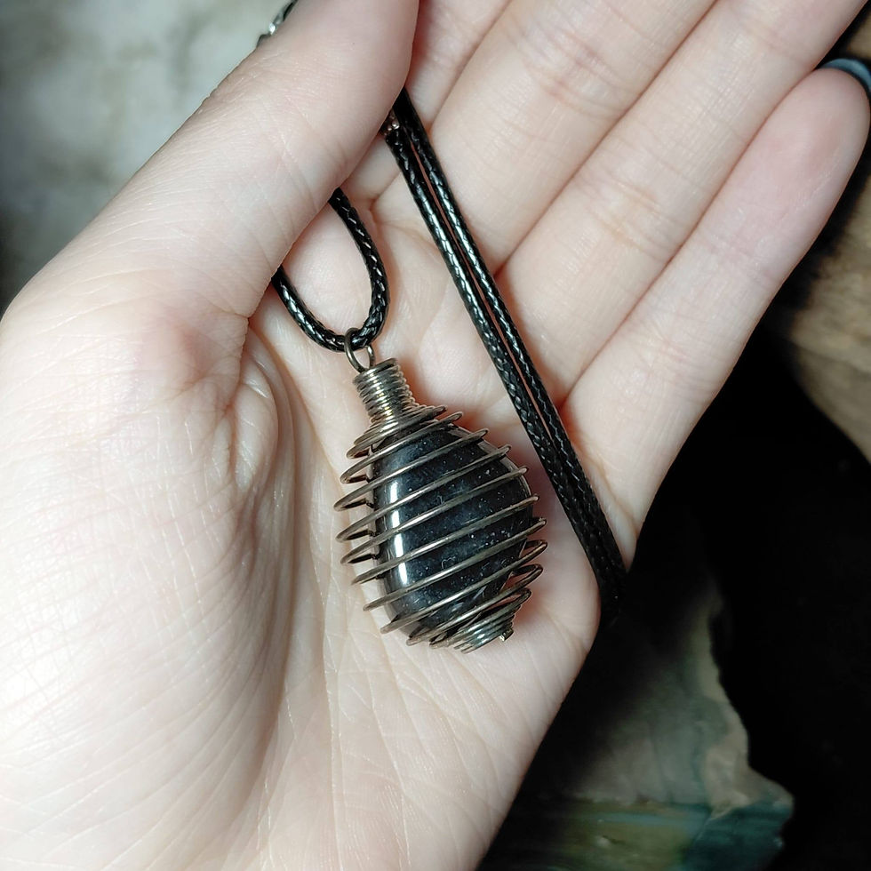 hematite tumblestone in a wire cage on a cord hand held
