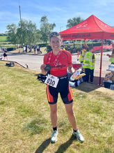 Me stood in my trisuit with my medal at the finish line from my first (super sprint) triathlon.
