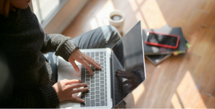 Mulher trabalhando em home-office despojadamente com café ao lado e seu celular smartphone