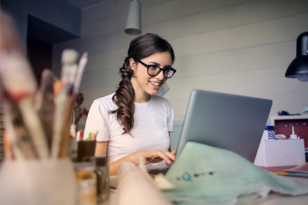 Jovem moça contente com seu trabalho home office no seu quarto