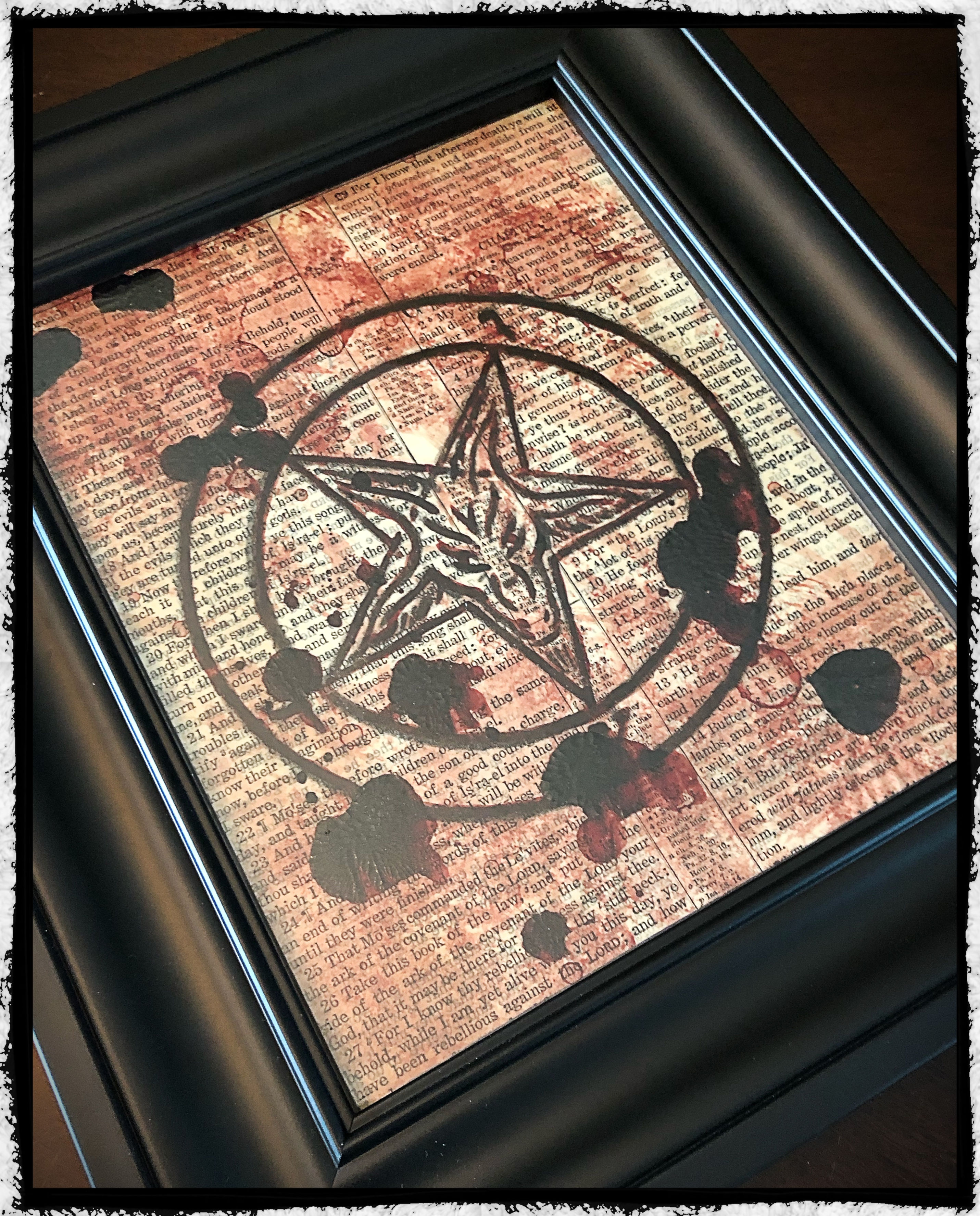 Framed real blood baphomet on vintage bible page.