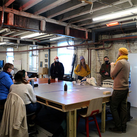 Tutor Phil Gomm teaching students who are stood around a square table