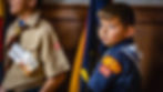 young cub scout standing with a flag during a ceremony