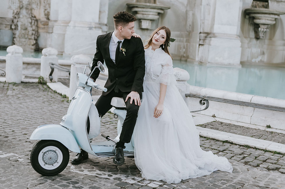 Editorial wedding photography in Rome featuring a bride in a flowing white gown and groom in a black suit posing with a vintage Vespa at Fontana dell’Acqua Paola.