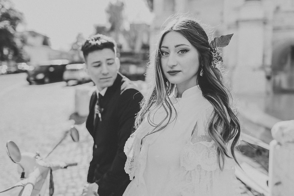Black-and-white wedding portrait of bride in lace gown with groom blurred in the background, Rome.