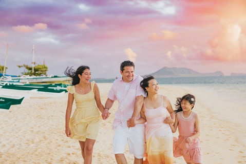 Family walking on Oahu beach at sunrise during a candid Hawaii photography session.