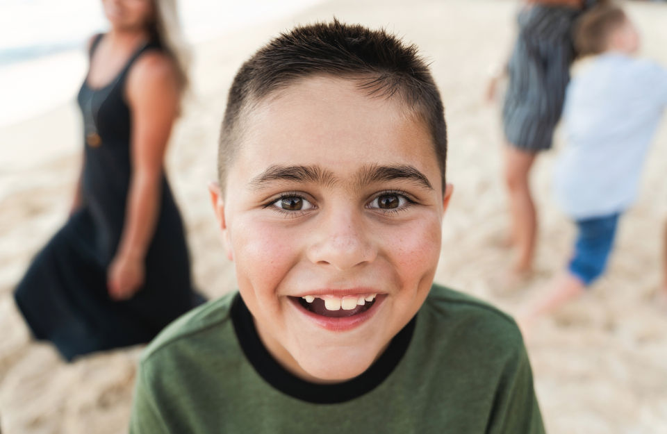 A kid gives a big toothless grin during his family photo session. .